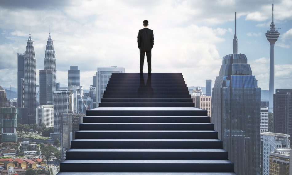 Back view of man standing on stairs on blurry city background. Success and growth concept